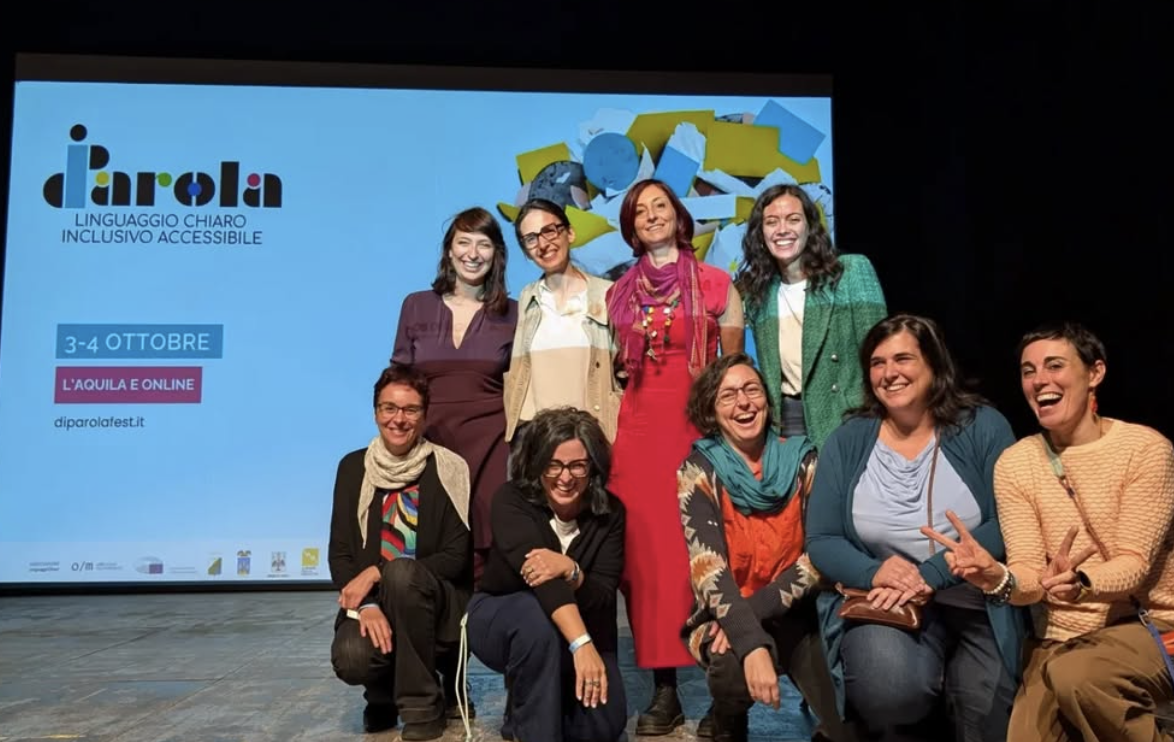 Un gruppo di donne vestite in abiti colorati è su un palcoscenico e sorride